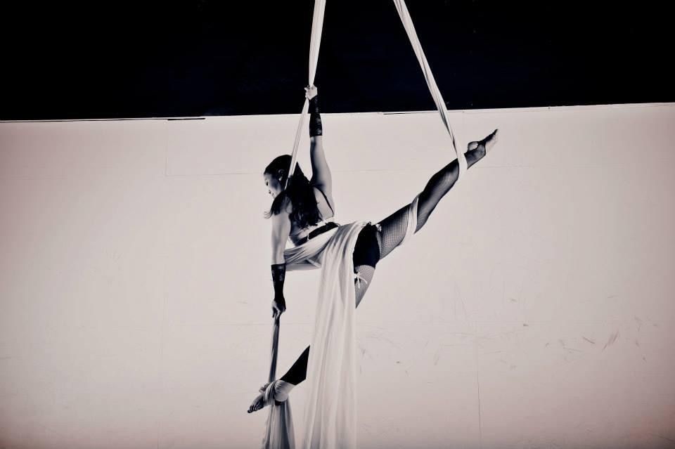 woman hanging from silk posing for black and white photoshoot doing extreme split, aerial silk classes, aerial silks