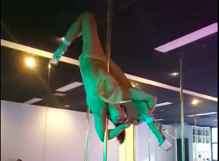 video image of woman performing pole routine at The Pole Room CBD Studio in heels under green lights, aerial fitness