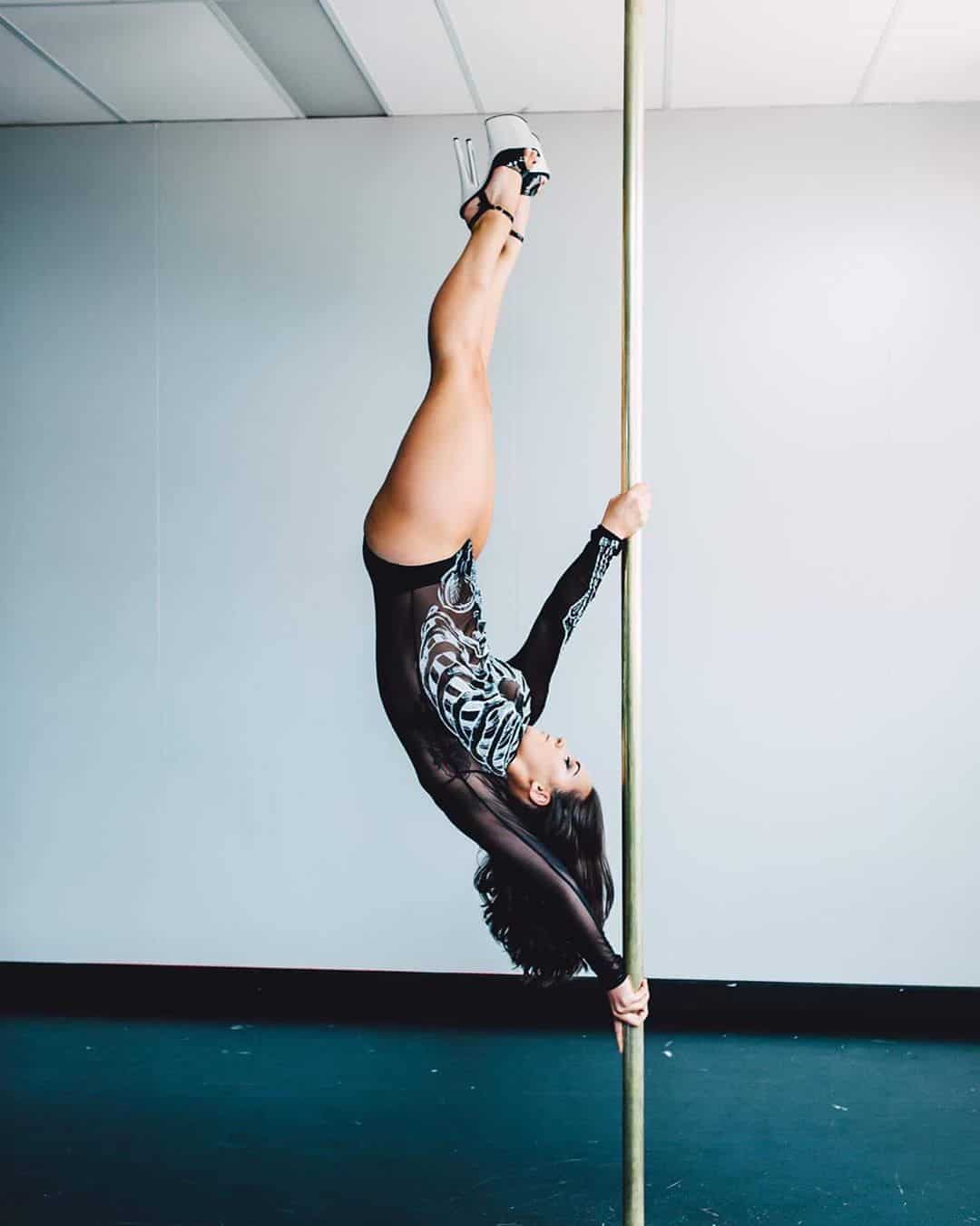woman upside down on pole for photoshoot wearing heels and skeleton outfit