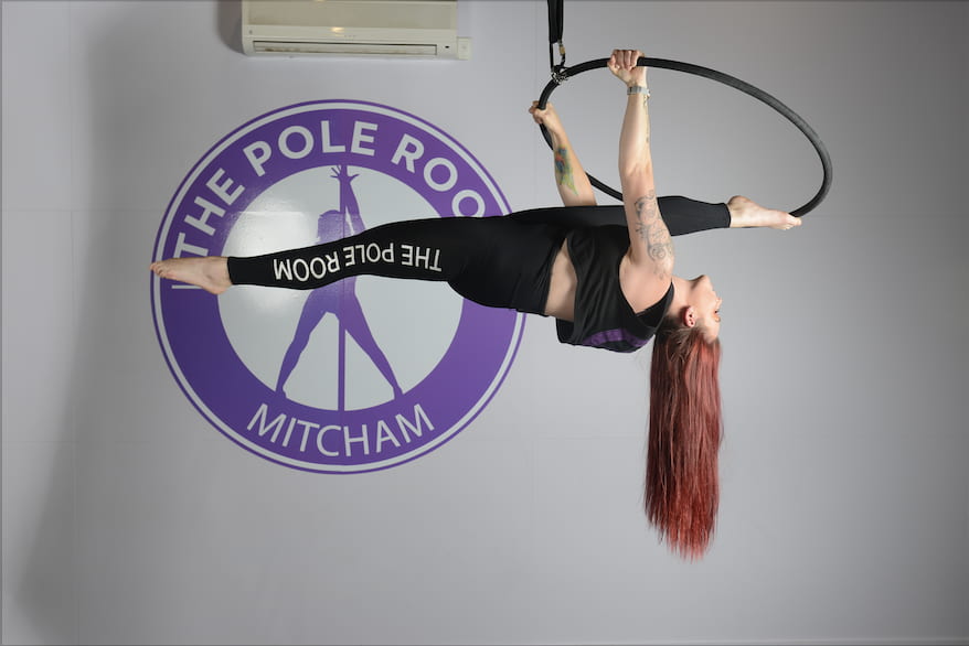 Woman on Lyra hoop splits trick in studio upside down, aerial classes, aerial silk classes, aerial silks, aerial fitness