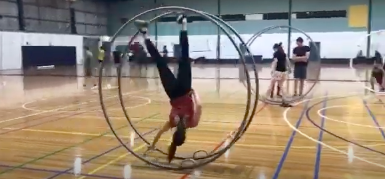 video image of woman training German wheel at a gym, aerial fitness, aerial silks, aerial silk classes, aerial classes